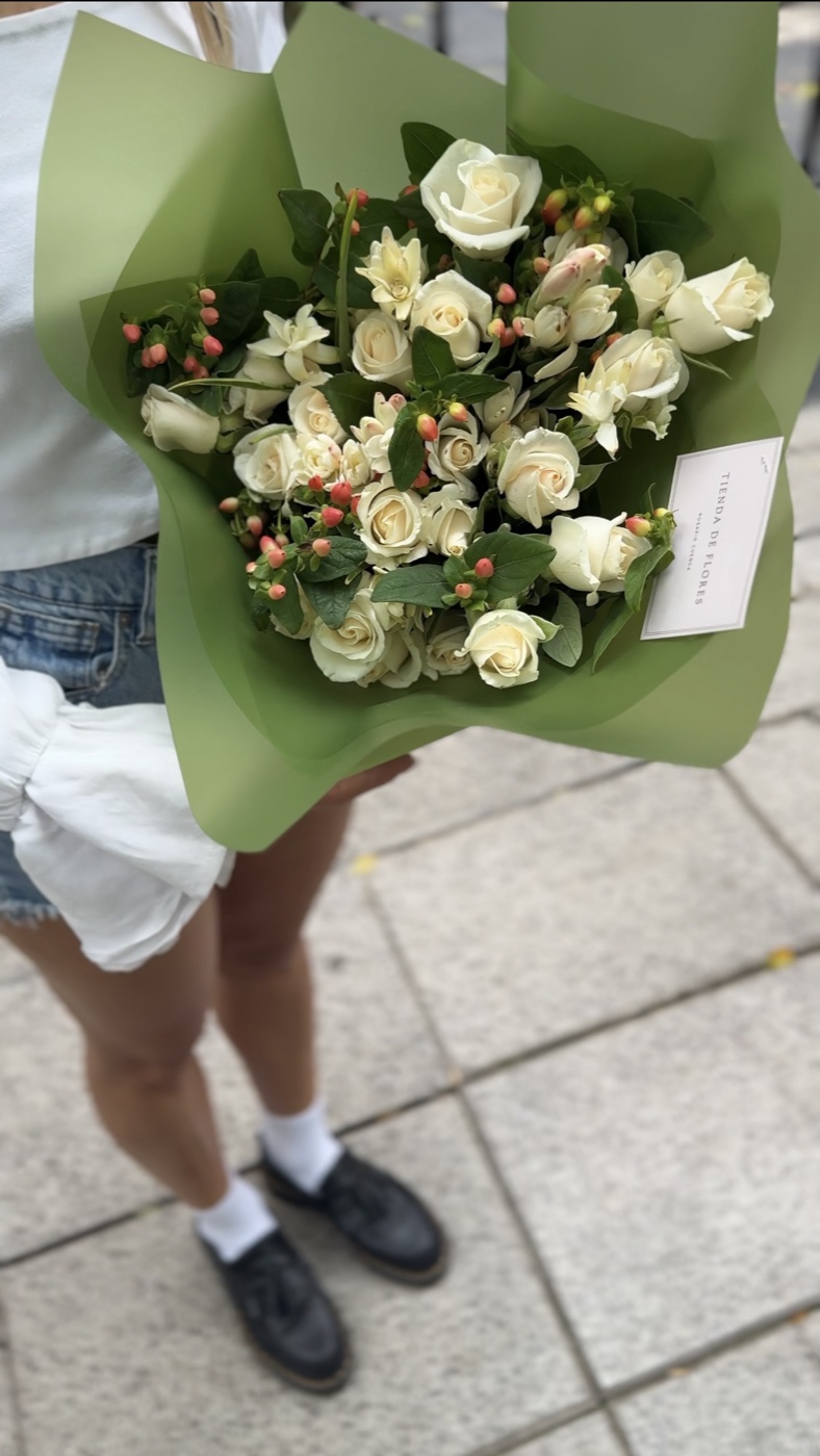 Ramo de rosas blancas e hypericum en papel verde